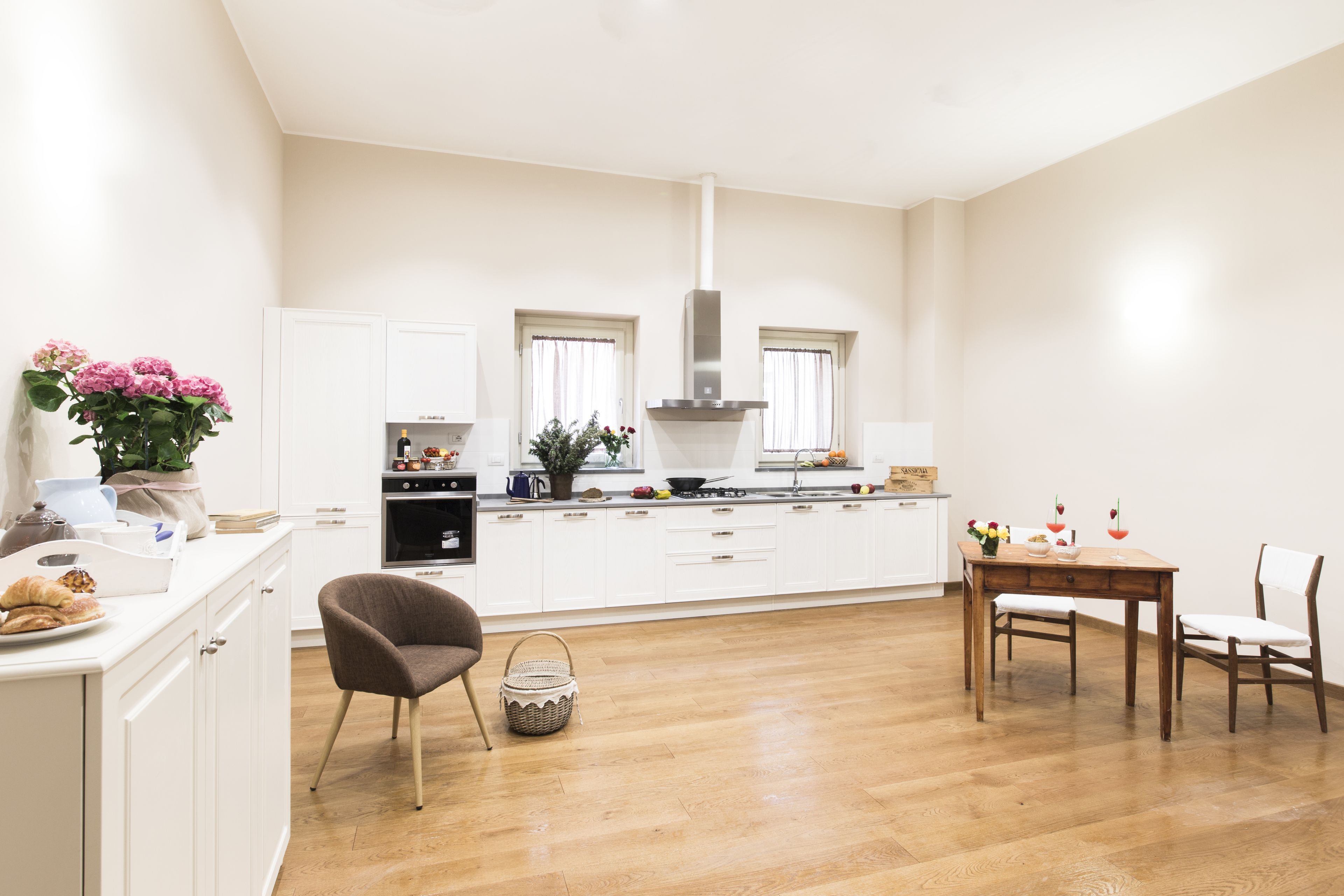 A modern kitchen with white cabinetry, a central island, and a dining area with a wooden table and chairs.