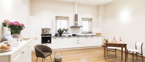 A modern kitchen with white cabinetry, a central island, and a dining area with a wooden table and chairs.