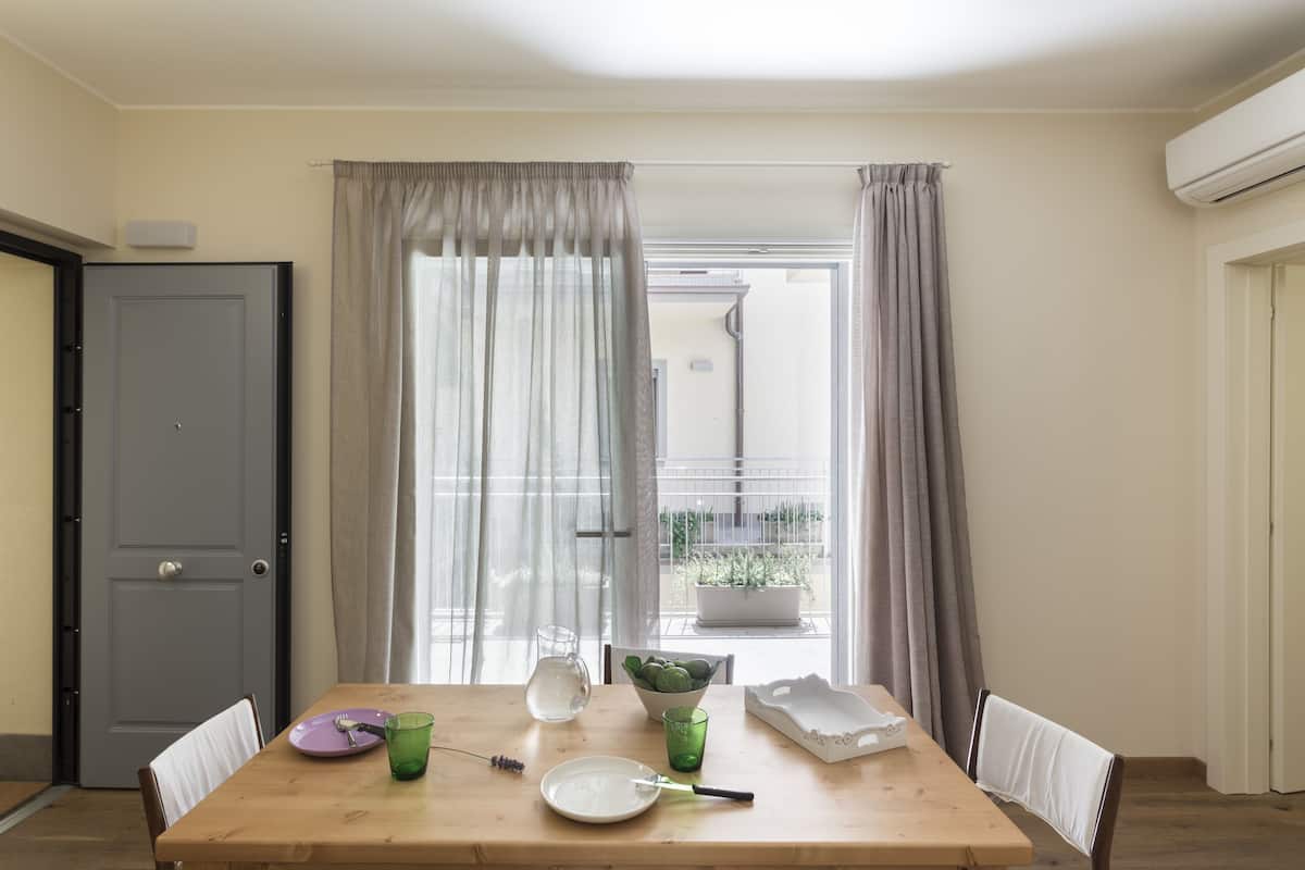 Un coin repas avec une table en bois, des chaises, un bol, une assiette, un verre et une carafe.