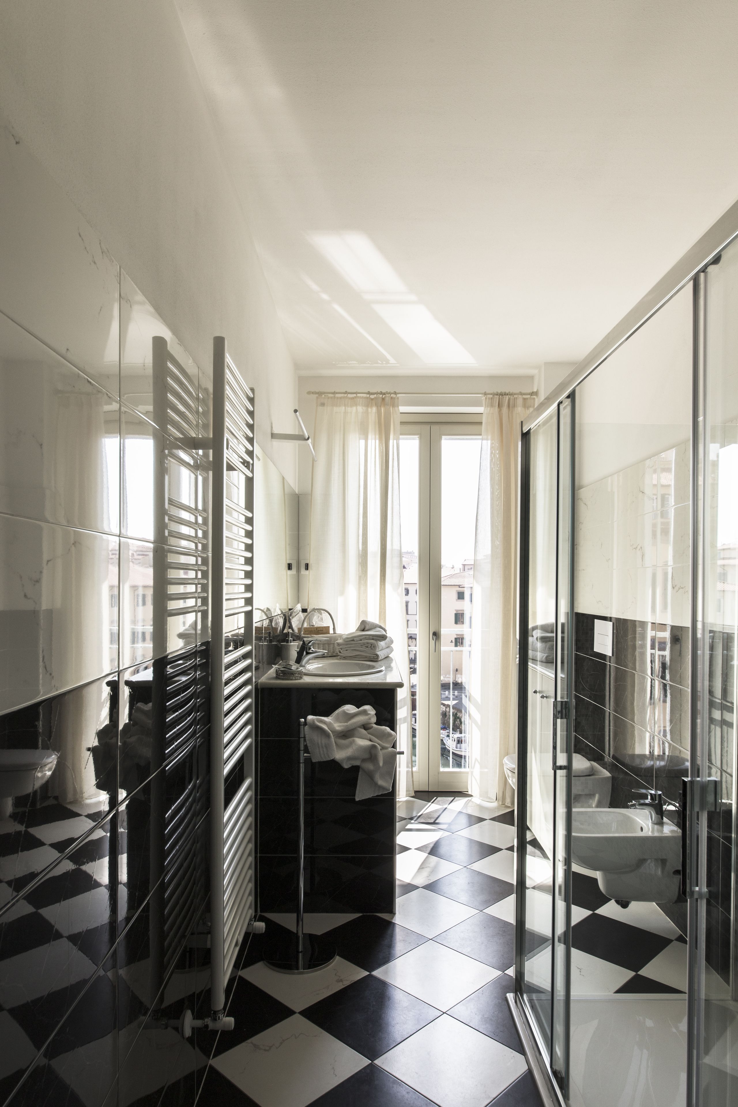Une salle de bain moderne avec un carrelage noir et blanc à motifs géométriques, une douche en verre et un grand miroir.