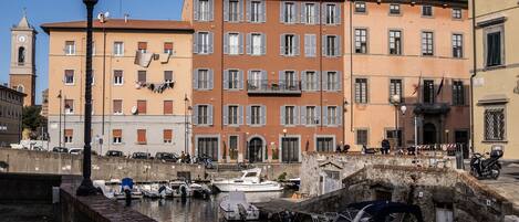 Un bâtiment situé au bord de l’eau, doté de nombreux balcons, d’une tour horloge et d’un port de plaisance avec des bateaux.