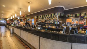 Una zona de bar con una barra alargada, varias llaves de cerveza y una gran variedad de botellas y vasos.