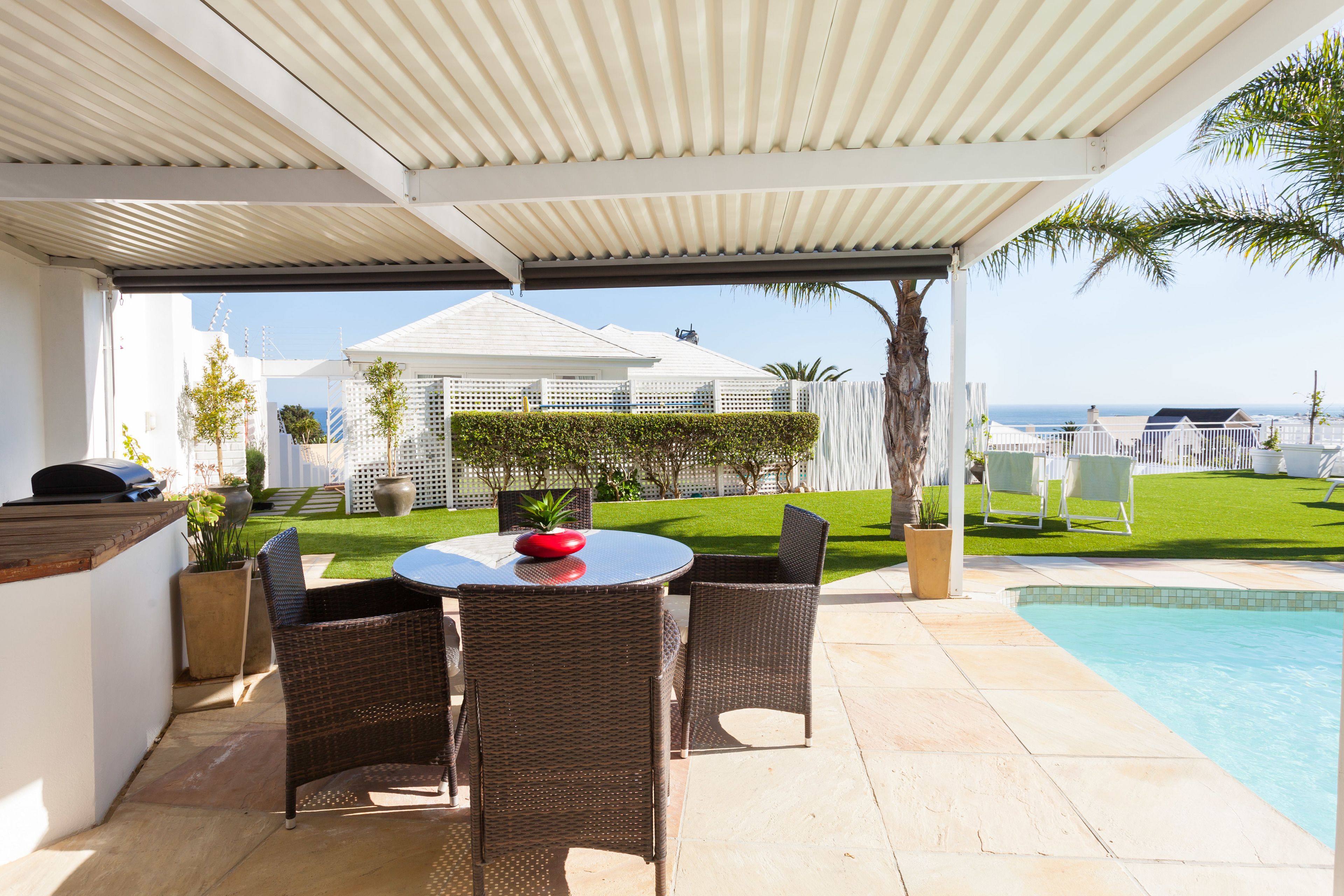 Eine Terrasse im Freien mit Pool, Korbmöbeln und Meerblick.