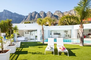 A modern house with a pool, white furniture, and a view of mountains. - Funkey Villas (Cape Town)