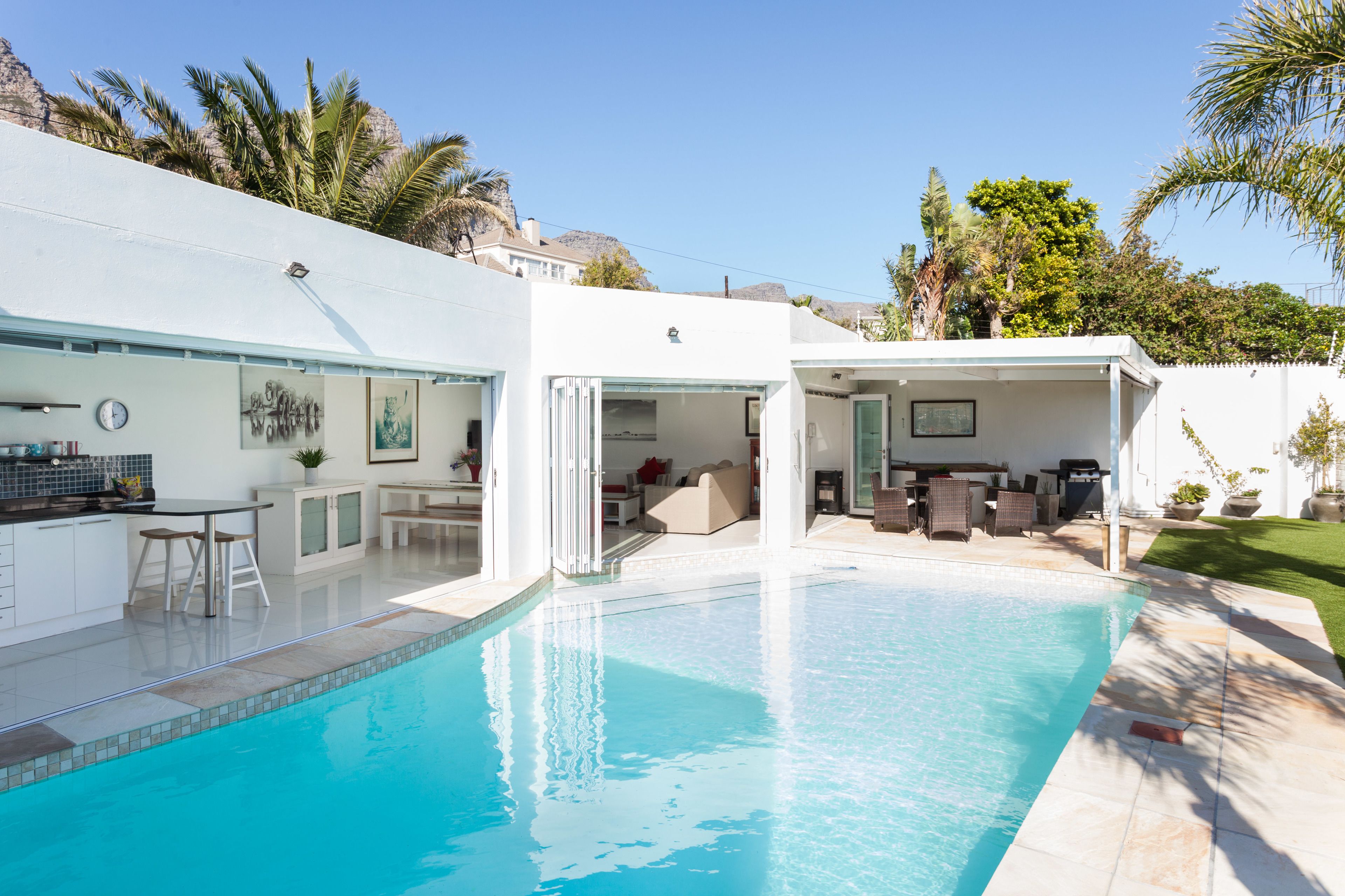 Una casa moderna con piscina, zona de estar exterior y patio.