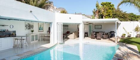 Una casa moderna con piscina, zona de estar exterior y patio.