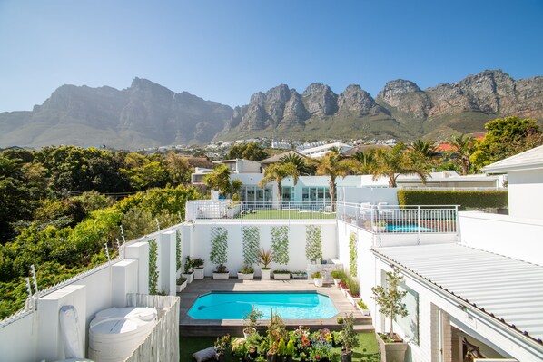 A residential area with a swimming pool, white buildings, and mountains in the background. - Funkey Villas (Cape Town)