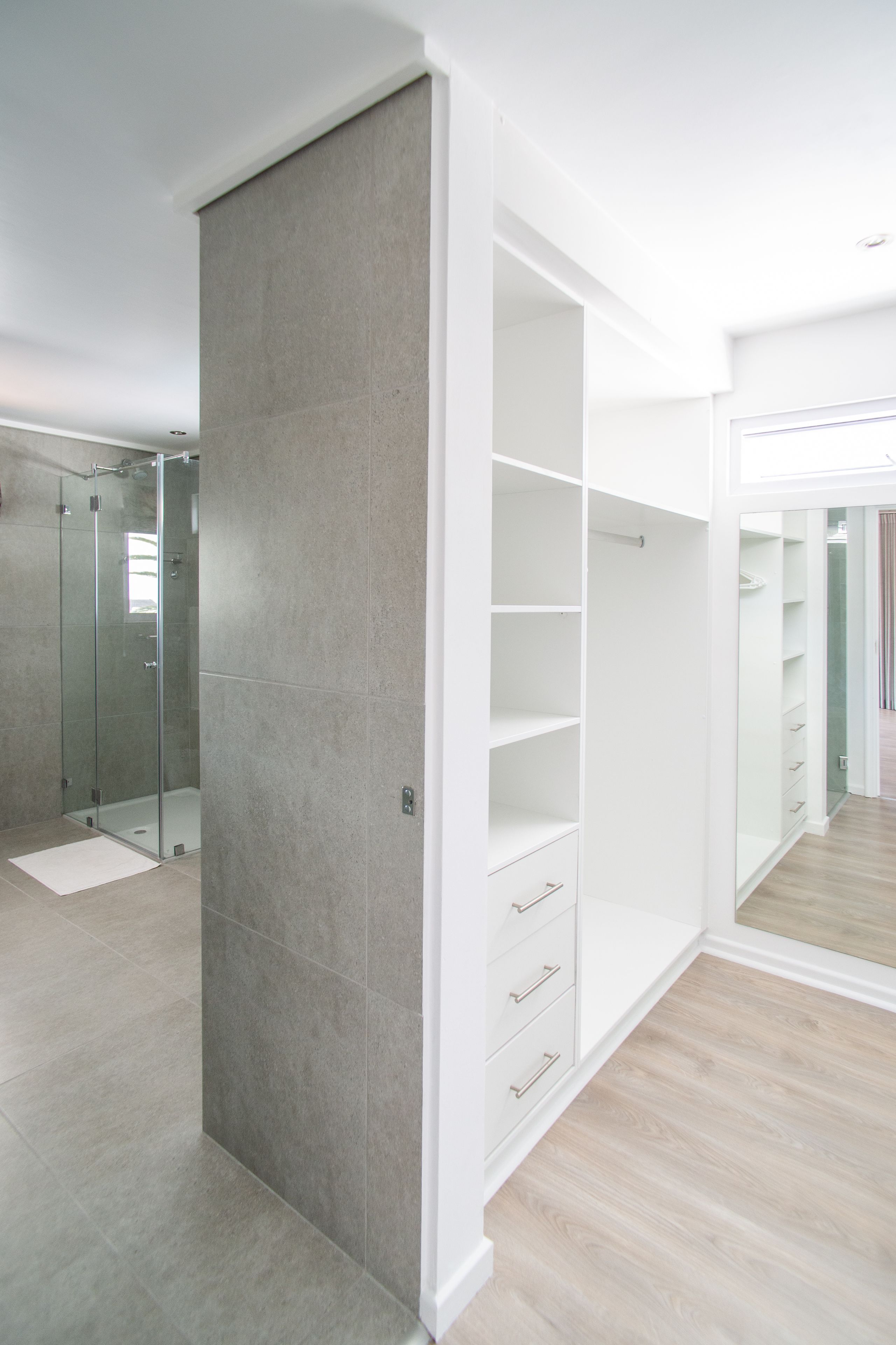 A modern bathroom with a glass shower enclosure, a white vanity, and a large mirror.