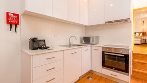 Een moderne keuken met witte kastjes, een magnetron, een oven en een spoelbak.
