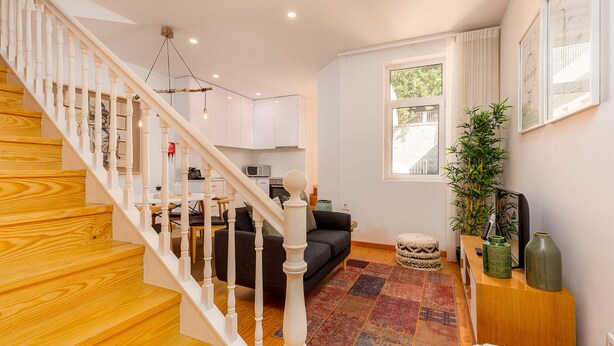 Een moderne woonkamer met een trap, een bank, een salontafel en een groot raam.