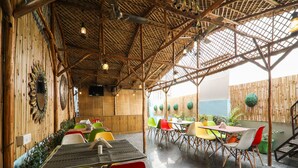 An outdoor dining area with bamboo walls, colorful chairs, and tables. - OYO 15567 Hotel India International Sitare (New Delhi)