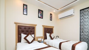A hotel room with two beds, each with a wooden headboard and white bedding. There is an air conditioning unit on the wall and a framed artwork above the beds. - OYO 15567 Hotel India International Sitare (New Delhi)