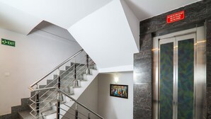 A modern interior with a staircase, an elevator, and a welcome mat. - OYO 15567 Hotel India International Sitare (New Delhi)