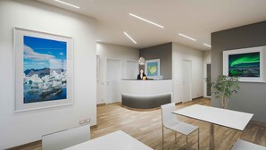 A modern reception area with a receptionist desk, framed pictures on the walls, and a wooden floor. - Hotel Selja (Rangárþing eystra)