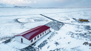 A snow-covered landscape with a building featuring a red roof and white walls. - Hotel Selja (Rangárþing eystra)