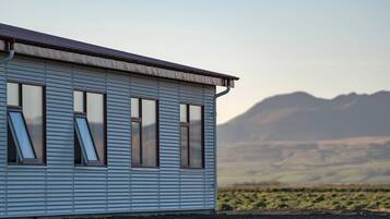 Un edificio con fachada de metal corrugado y varias ventanas, con montañas al fondo.