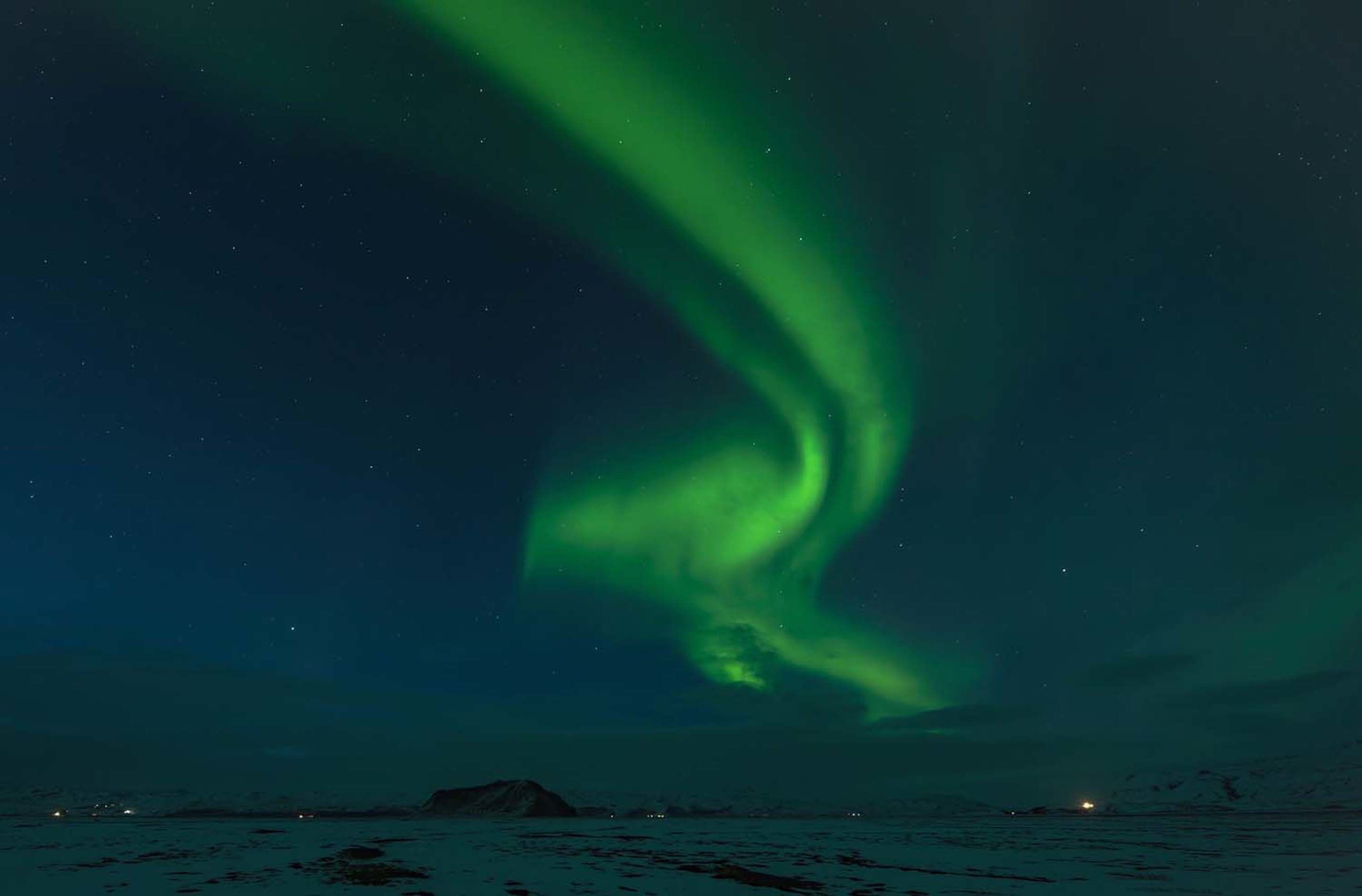 Een nachtelijke hemel met het noorderlicht boven een besneeuwd landschap.