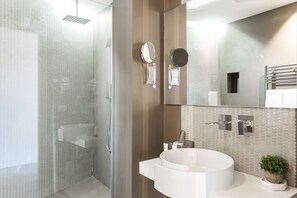 A modern bathroom with a glass shower enclosure, a white sink with a mirror, and a small potted plant on the counter. - A World Aparts - Barberini Boutique Hotel (Rome)