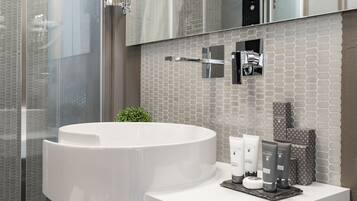 Un baño moderno con un lavabo grande de color blanco, cabina de ducha con paredes de cristal y un salpicadero de azulejos.