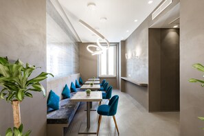 A modern dining area with a long table, blue chairs, and a bench with blue cushions. - A World Aparts - Barberini Boutique Hotel (Rome)