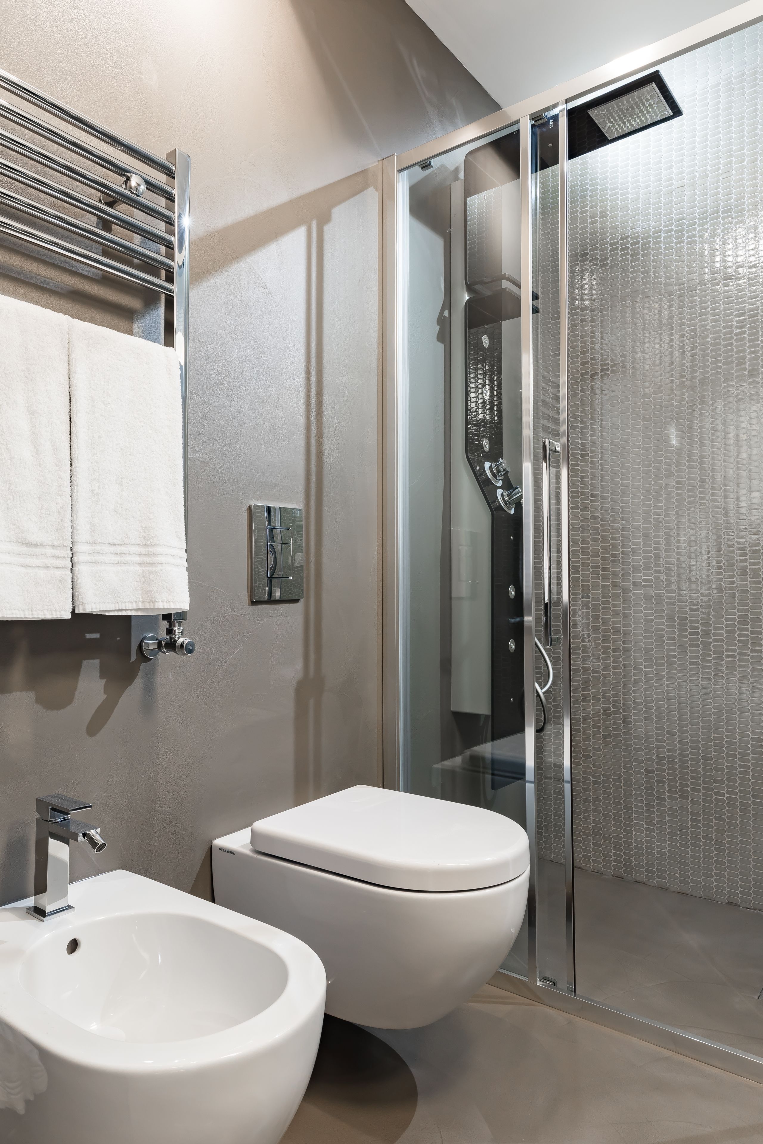Un baño moderno con cabina de ducha de vidrio, inodoro blanco y un lavabo grande de color blanco.