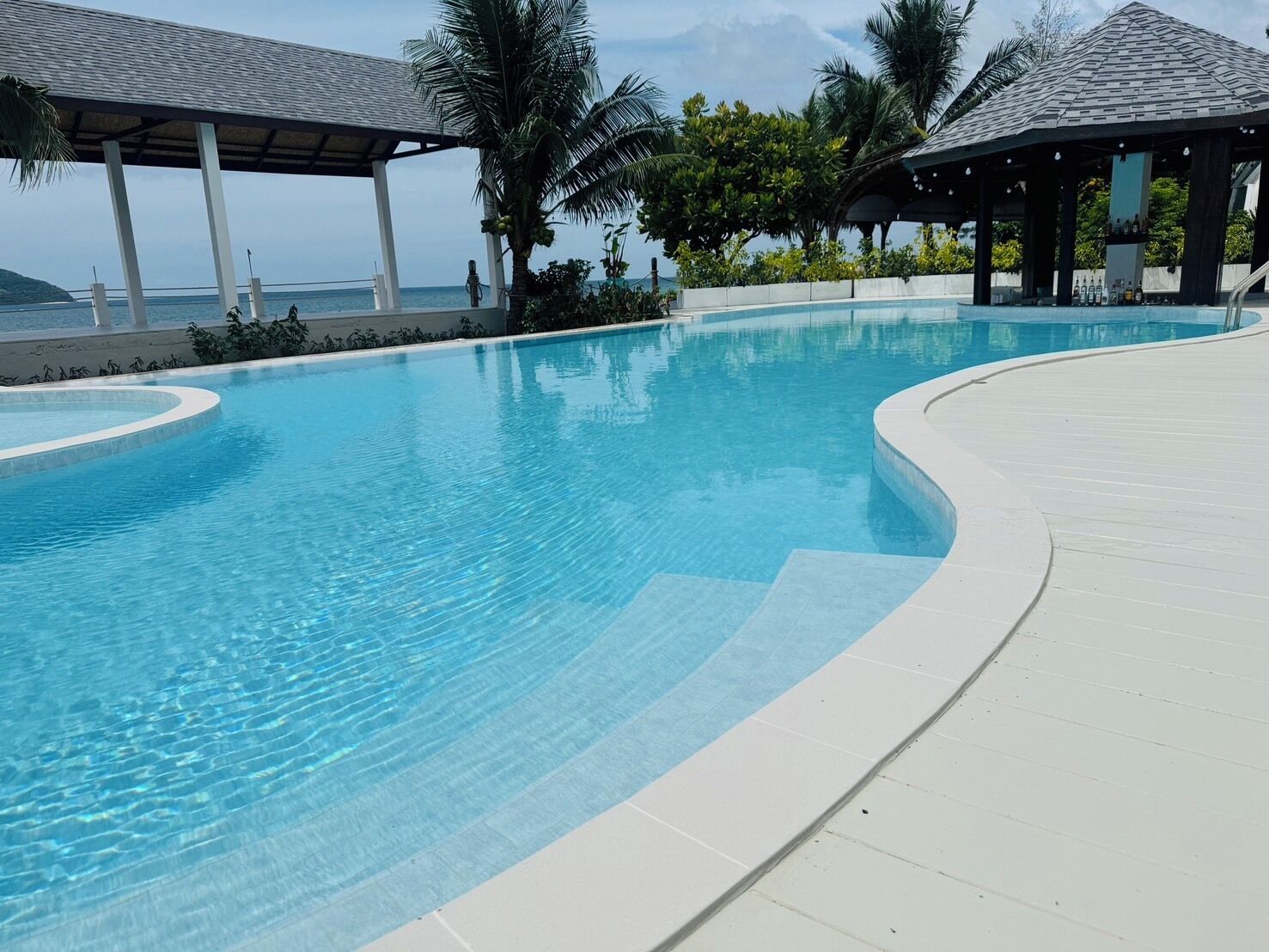 Una piscina al aire libre, sombrillas, sillones reclinables de piscina
