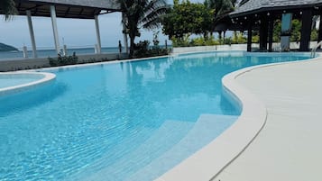 Una piscina al aire libre, sombrillas, sillones reclinables de piscina