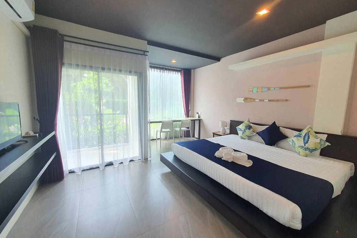 A modern hotel room with a large bed, a desk, and a TV.