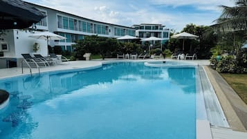 Una piscina al aire libre, sombrillas, sillones reclinables de piscina