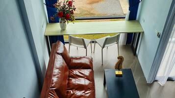 A balcony with a view of a swimming pool, a brown leather sofa, a small table, and a vase of flowers.