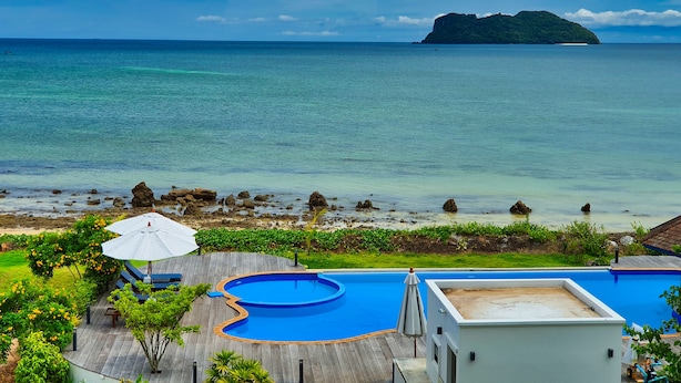 A pool area with a view of the ocean and an island. - The Beach Resort & Residence (Pathio)