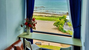 A room with a view of the sea, a brown leather sofa, and a table with chairs. - The Beach Resort & Residence (Pathio)