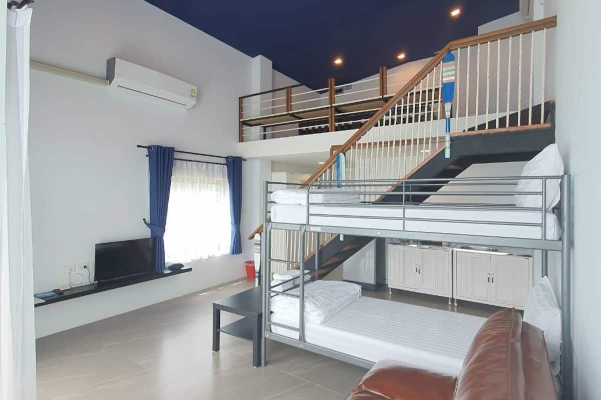 A modern, multi-level room with bunk beds, a staircase, a flat-screen TV, and a sofa.