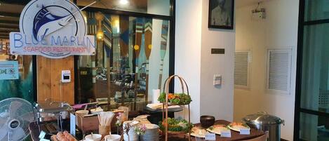 Ein reichhaltiges Buffet mit verschiedenen Speisen und ein Schild für ein Fischrestaurant.