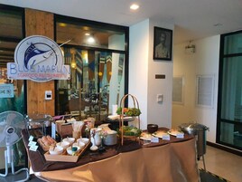 Montaje de bufé con diversos platos y el letrero de un restaurante de mariscos.