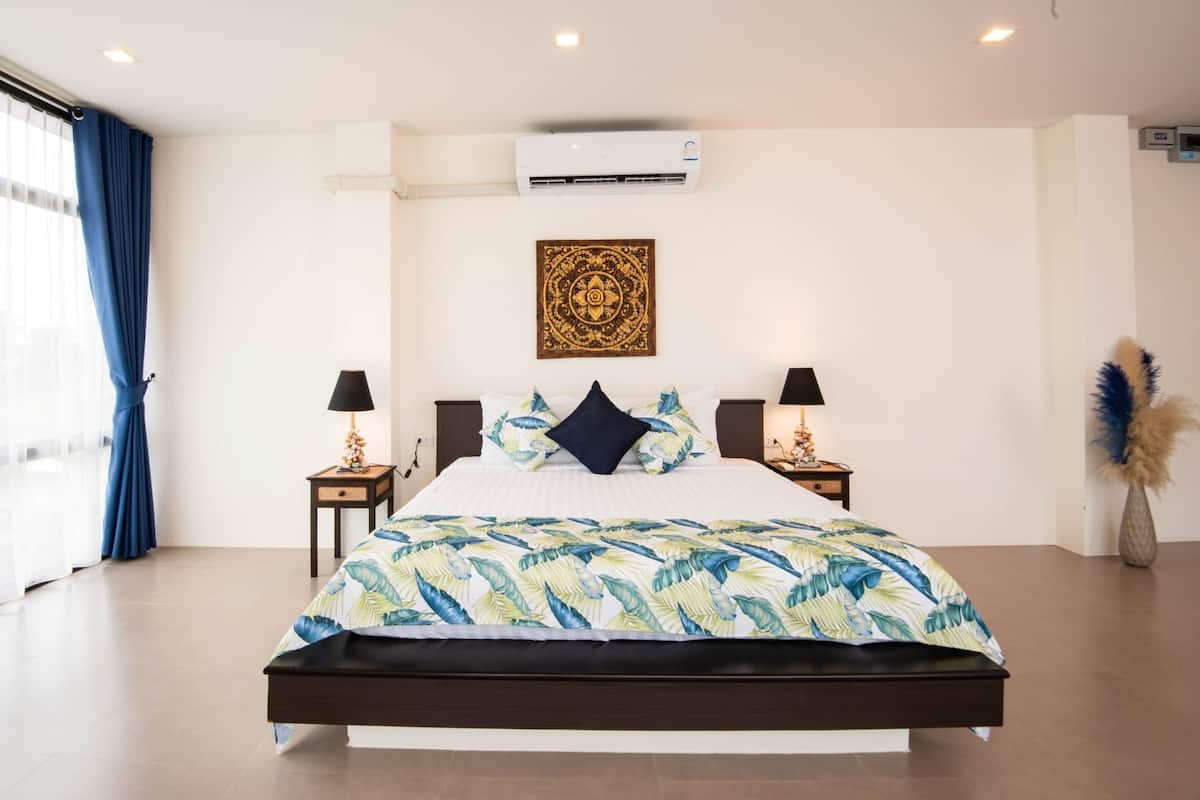 A modern hotel room with a large bed, air conditioning, decorative wall art, and two bedside tables with lamps.