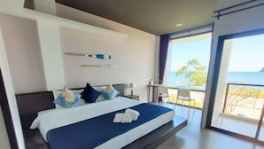 A modern hotel room with a large bed, a desk, and a view of the sea. - The Beach Resort & Residence (Pathio)