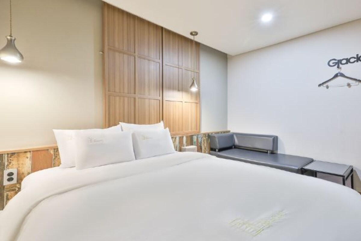 A hotel room with a large bed, a desk, and a wardrobe.