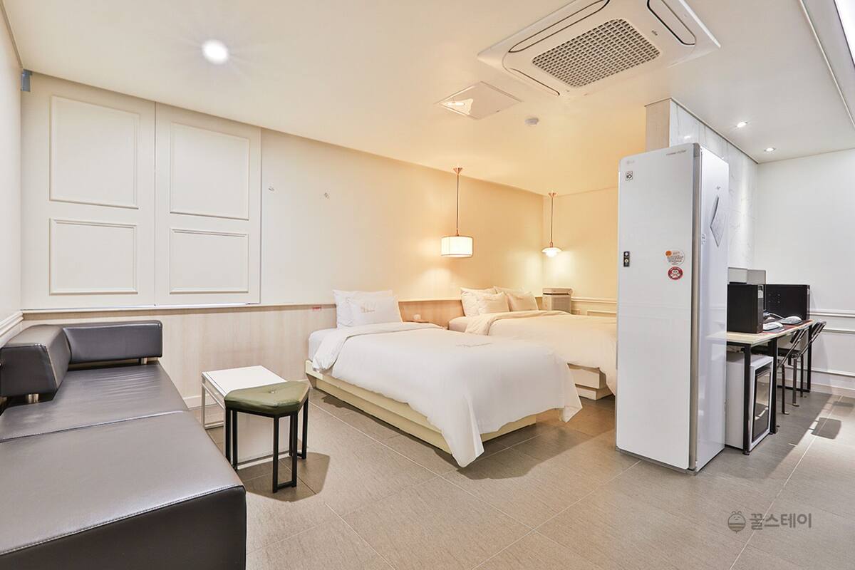 A hotel room with a bed, bedside tables, a desk, and a chair.