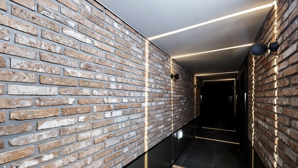 A corridor with exposed brick walls and modern lighting fixtures. - Gracias Hotel Gimhae (Gimhae)