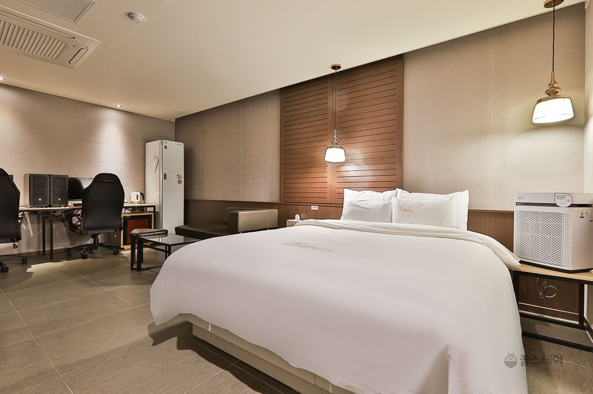 A hotel room with a large bed, a desk with a chair, a refrigerator, and a microwave.