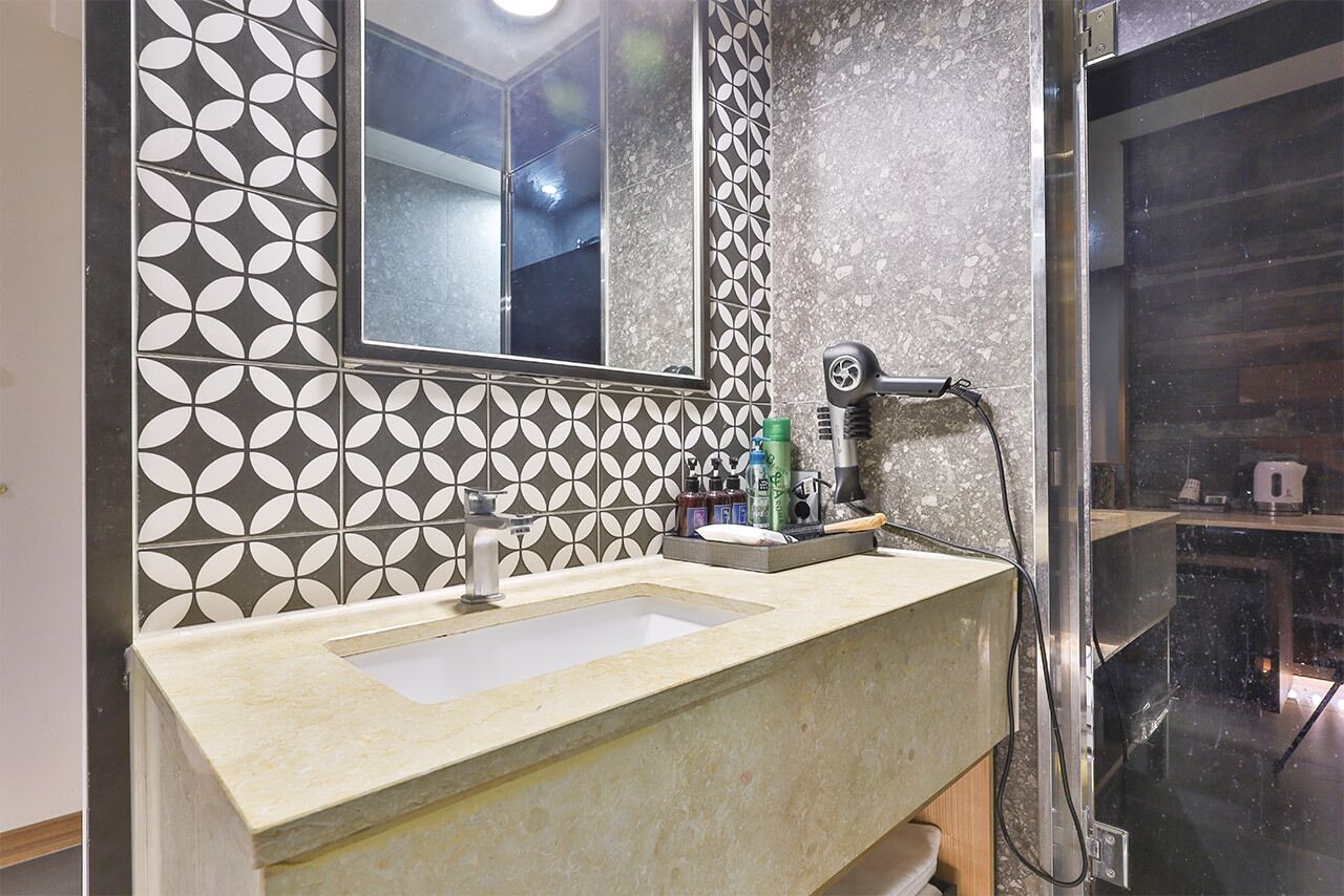 A bathroom with a sink, mirror, and shower area.