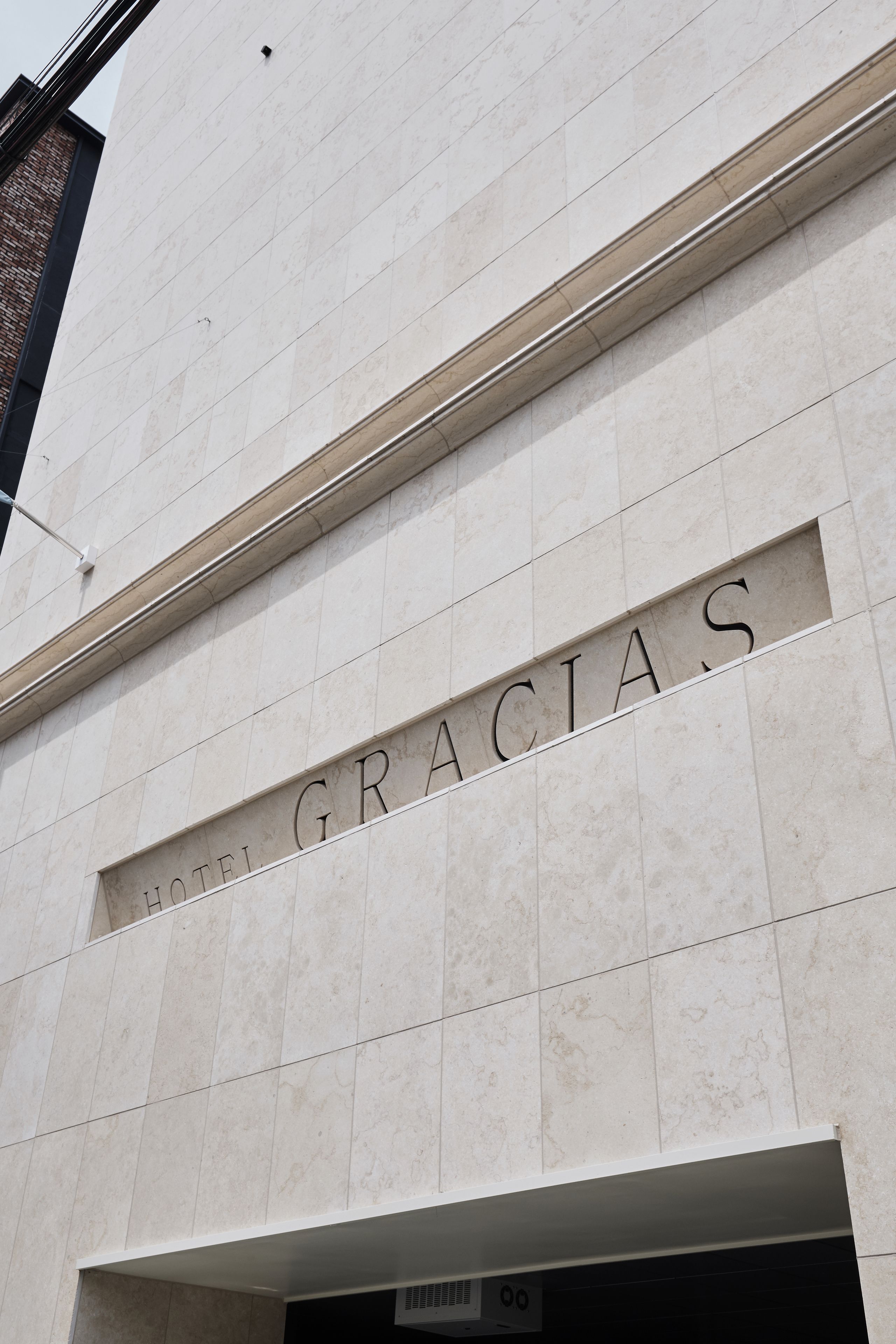 Fachada de edificio con la inscripción “HOTEL GRACIAS” grabada en una línea horizontal.