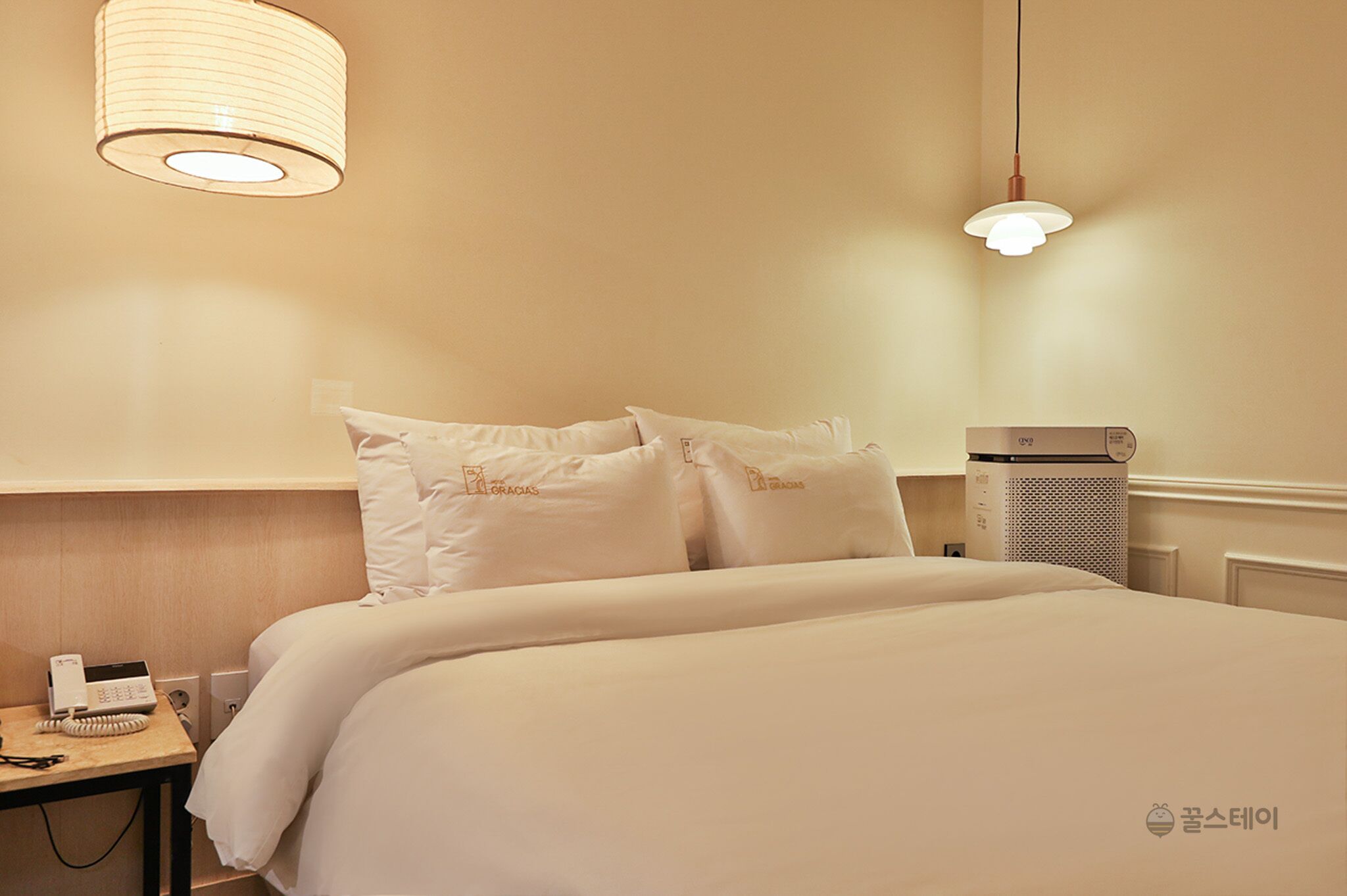 Une chambre d’hôtel avec un lit bien fait, un téléphone sur la table de chevet et un radiateur fixé au mur.