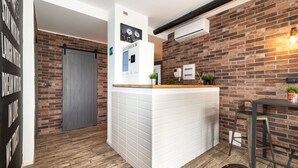 A reception area with a white counter, a brick wall, and a door. - co.sleep (Rome)