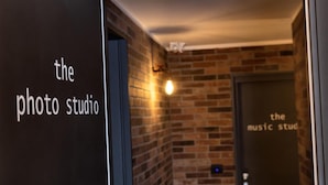 A hallway with a brick wall and a door labeled "the music studio." - co.sleep (Rome)
