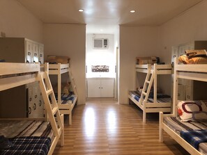 A dormitory room with bunk beds, wooden floors, and a kitchenette in the center. - Alesseo Backpackers - Hostel (Puerto Princesa)