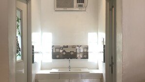 A narrow hallway with a white sink and cabinets, a window with blinds, and a ceiling vent. - Alesseo Backpackers - Hostel (Puerto Princesa)