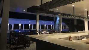 A modern bar area with a long counter, seating, and a unique ceiling design. - Alesseo Backpackers - Hostel (Puerto Princesa)