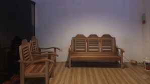 A room with a wooden bench and two chairs against a white wall. - Alesseo Backpackers - Hostel (Puerto Princesa)